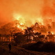 A man stands in front of a wild fire in Schinos, west of Athens, on May 19, 2021.